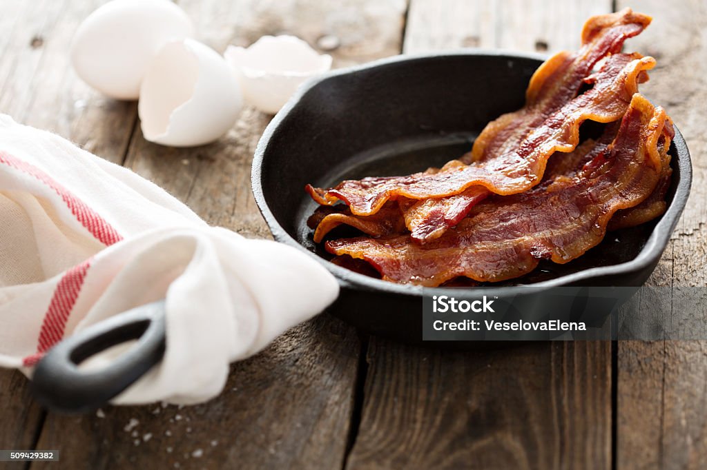 Sizzling hot bacon in a cast iron skillet Sizzling hot bacon pieces in a cast iron skillet Bacon Stock Photo
