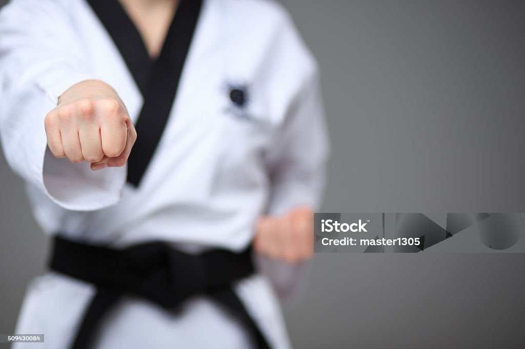 The karate girl with black belt The hand of karate girl in white kimono and black belt training karate over gray background. Karate Stock Photo