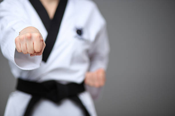 The karate girl with black belt The hand of karate girl in white kimono and black belt training karate over gray background. taekwondo photos stock pictures, royalty-free photos & images