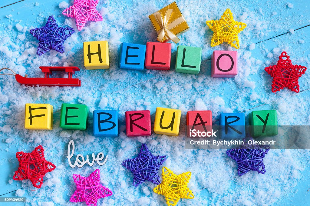 writing hello february on toy wooden colour cubes with decor writing hello february on toy wooden colour cubes with decor and light blue background. February Stock Photo