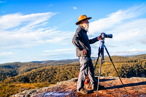 Photographer with camera and tripod on a ridge in the Australia outback, Blue Mountains National Park. Australia