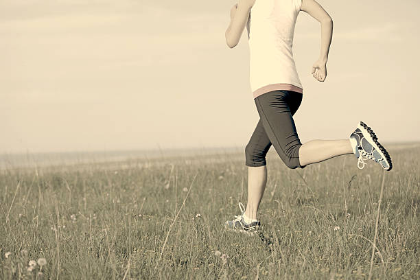 Runner athlete  running on sunrise/sunset grass field. woman fitness jogging workout wellness concept.