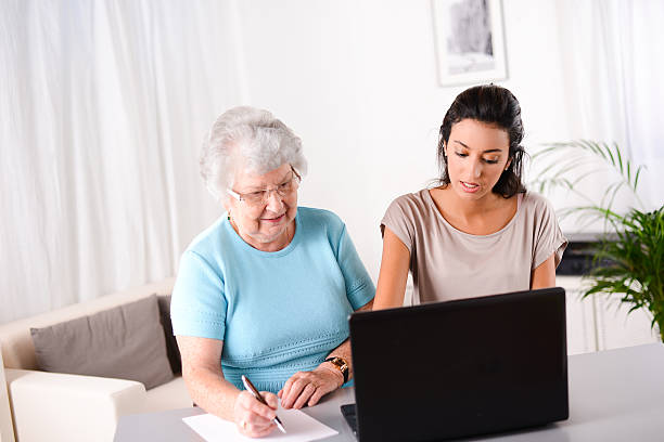 istock young woman helping elderly person with computer internet search email 509465965