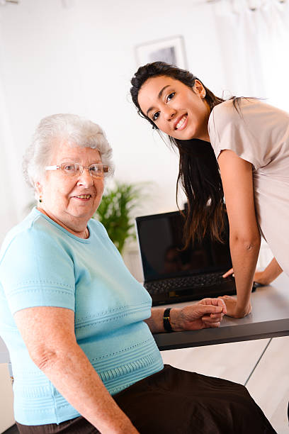 istock cheerful young woman teaching computer and internet to elderly person 509467613