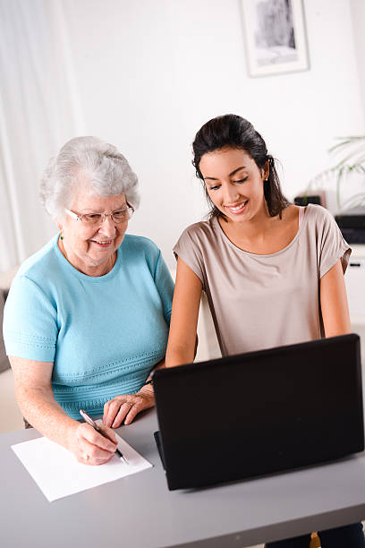 istock young woman helping elderly person with computer internet search email 509467725