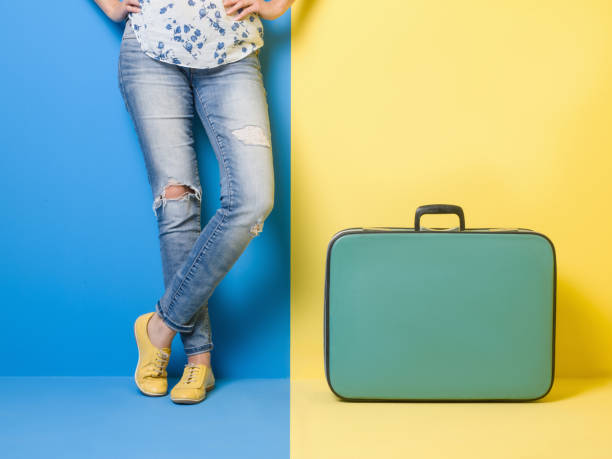 istock Woman stands beside suitcase painted background 509468814