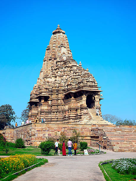People visit the Khajuraho Group of Monuments Khajuraho town, India - March 15, 2014. People visit the Khajuraho Group of Monuments in Khajuraho , India. Kandariya Mahadeva Temple. The Khajuraho Group of Monuments are a group of Hindu and Jain temples in Madhya Pradesh, India. The temples are famous for their Nagara-style architectural symbolism and their erotic sculptures. The Khajuraho Group of Monuments are one of the UNESCO World Heritage Sites in India. mahadeva-temple stock pictures, royalty-free photos & images