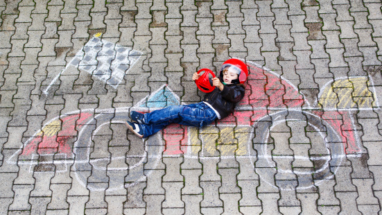 Creative leisure for children: Funny little child of four years having fun with race care picture drawing with chalk.