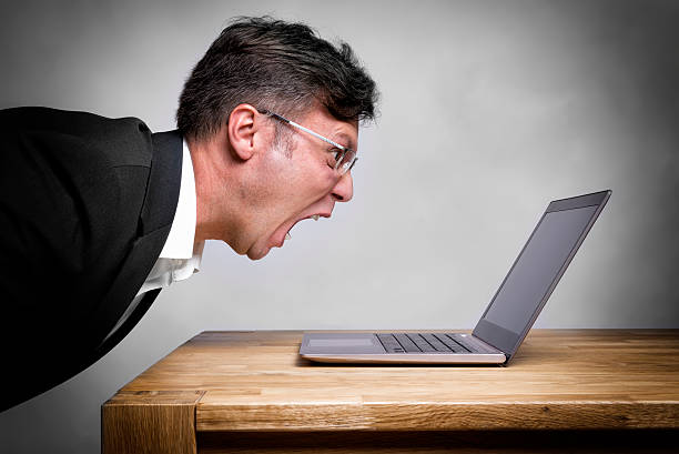 Man screaming at laptop stock photo