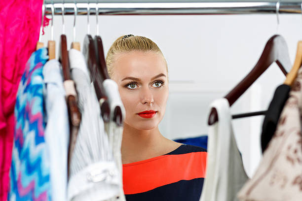 istock Beautiful thoughtful blonde woman standing inside wardrobe rack 509476524