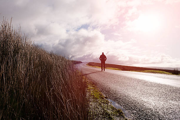 istock Man walking along an open Country road 509478262