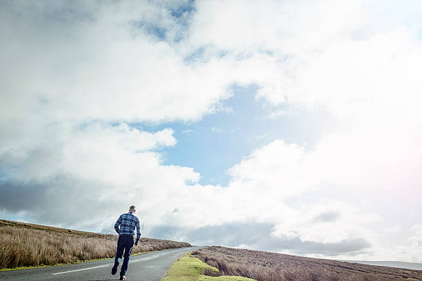 istock Man running along an open Country road 509480226