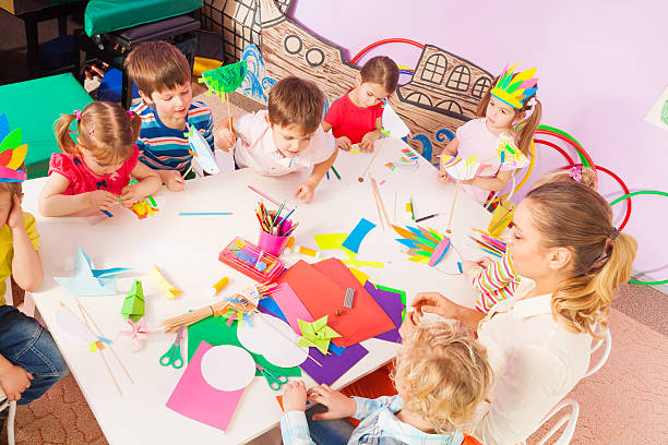 istock Group of kids and teacher by table view from above 509481654