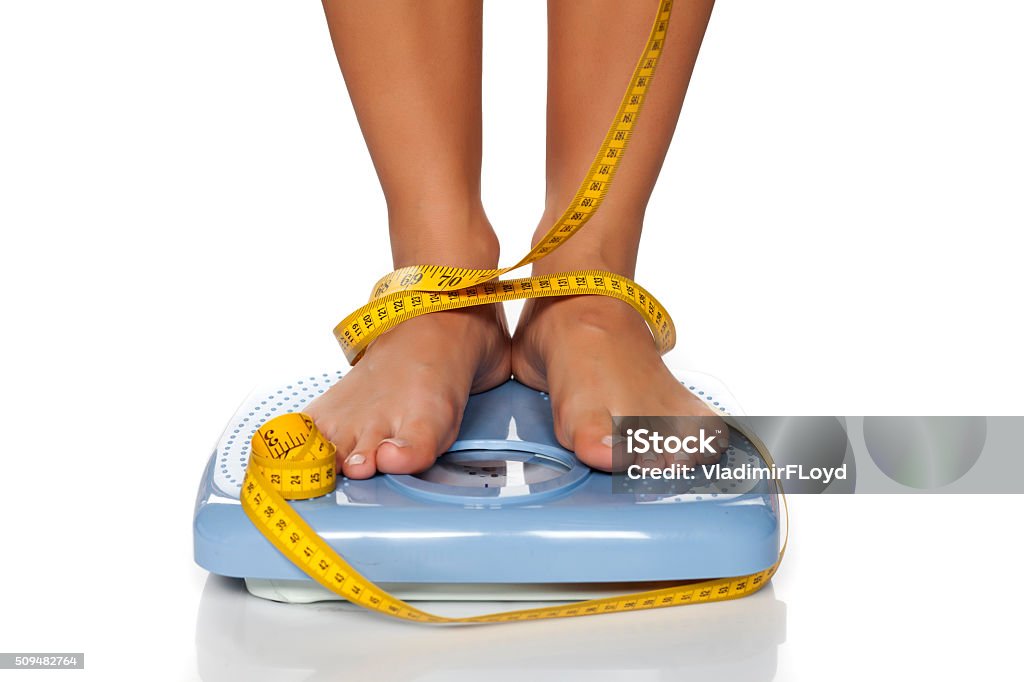 weight check woman's feet on a domestic weight scale and measuring tape around them Weight Scale Stock Photo