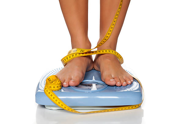 weight check woman's feet on a domestic weight scale and measuring tape around them woman defeat stock pictures, royalty-free photos & images