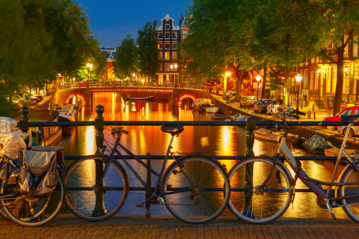 Night  illumination of Amsterdam canal and bridge with typical dutch houses, boats and bicycles, Holland, Netherlands.