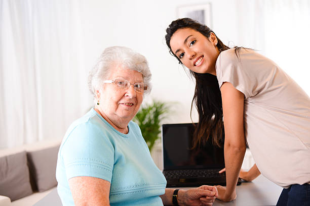 istock cheerful young woman teaching computer and internet to elderly person 509489351