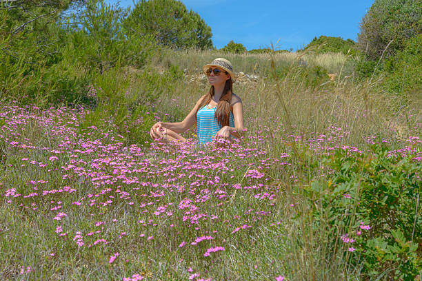 Young female meditating in a meadow of ping roses.