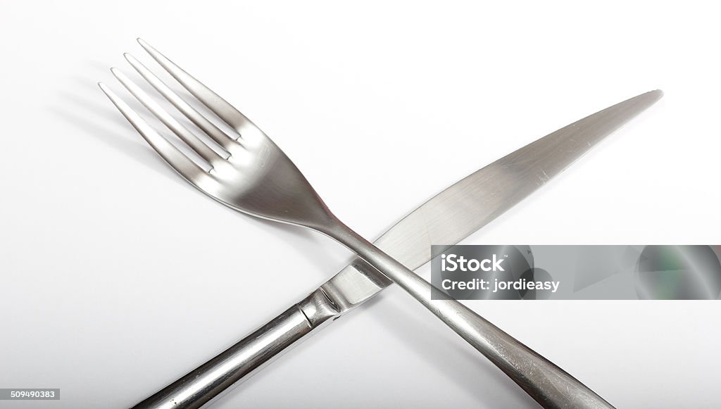 Crossed cutlery Metal fork and knife isolated on a white background with stylish shadows on a crossed position. Cross Shape Stock Photo
