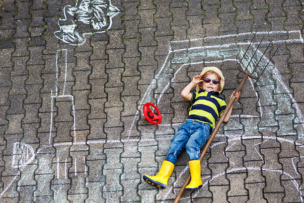 istock Little boy having fun with tractor picture drawing with chalk 509490883