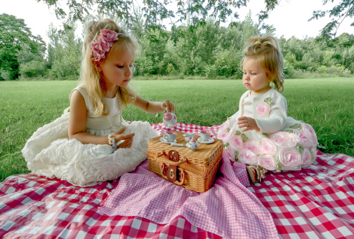 Two little girls having a tea party in the park.