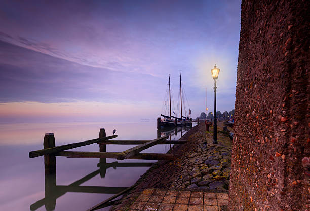 historical sailing boat at the entrance of the harbour of the Dutch fishing village Volendam in the early morning. Volendam is a popular tourist destination in the Netherlands, wellknown for its fishing boats and the traditional costume still worn by some residents; Volendam, Netherlands