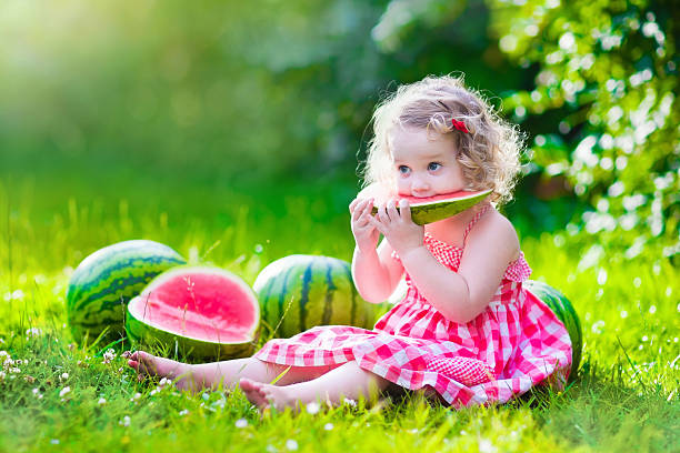 маленькая девочка ест арбуз - watermelon fruit healthy eating snack стоковые фото и изображения