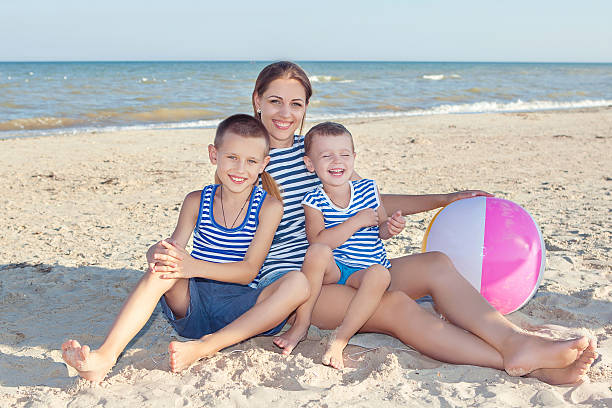 Madre e i suoi due figli avendo divertimento sulla spiaggia - foto stock