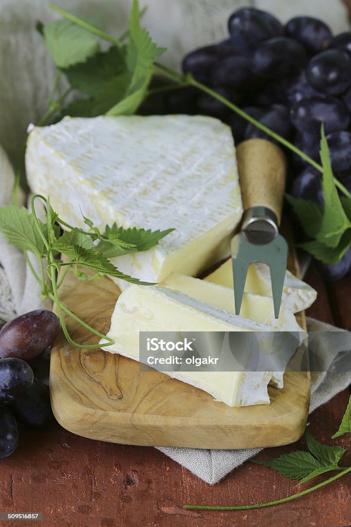 Soft brie cheese with sweet grapes on a wooden board Appetizer Stock Photo