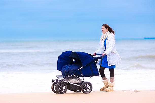 mutter und kinderwagen am strand mit zwei einzelbetten - gehen sportdisziplin stock-fotos und bilder