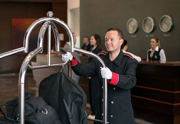 Bellboy working at a hotel Friendly bellboy working at a hotel carrying luggage on a cart and smiling bellhop stock pictures, royalty-free photos & images