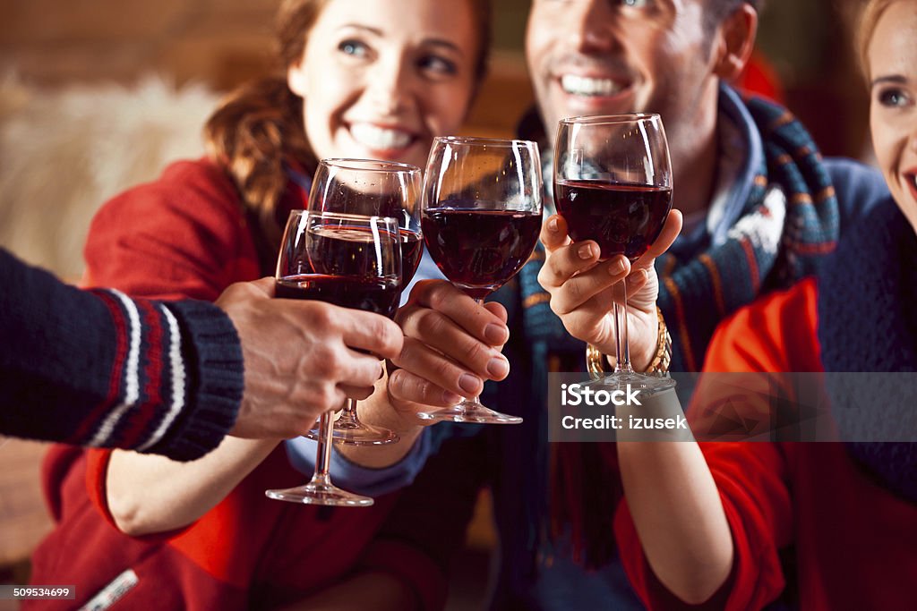 Friends toasting with wine Group of friends wearing warm clothes toasting with wine. Focus on wine glasses. Apres-Ski Stock Photo