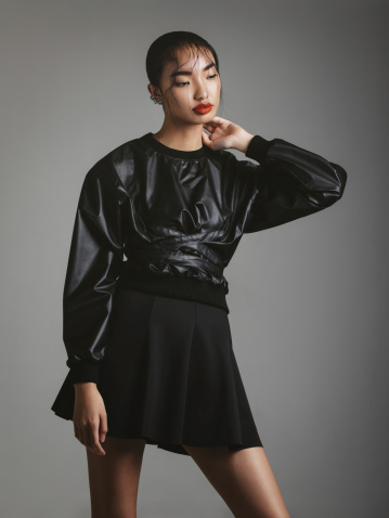 Portrait of asian fashionable woman wearing black leather top and skirt. Professional make-up and hairstyle.
