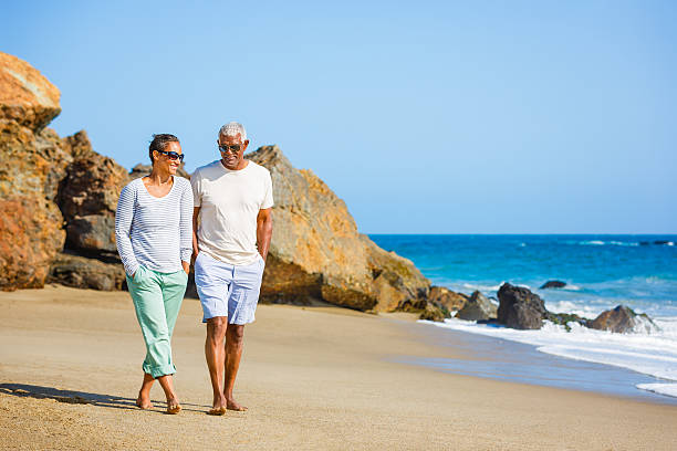 Senior African American couple walking on beach Senior African American couple walking with hands in pockets at sandy beach. Click for more similar images from this session. lypsela2013 stock pictures, royalty-free photos & images