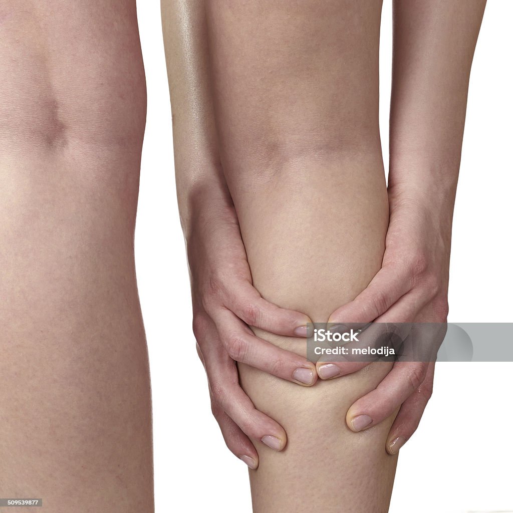 Acute pain in a woman knee. Acute pain in a knee. Woman holding hand to spot of knee-aches. Adult Stock Photo