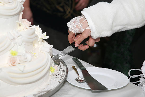 istock bride and groom cut the wedding cake closeup 509541636