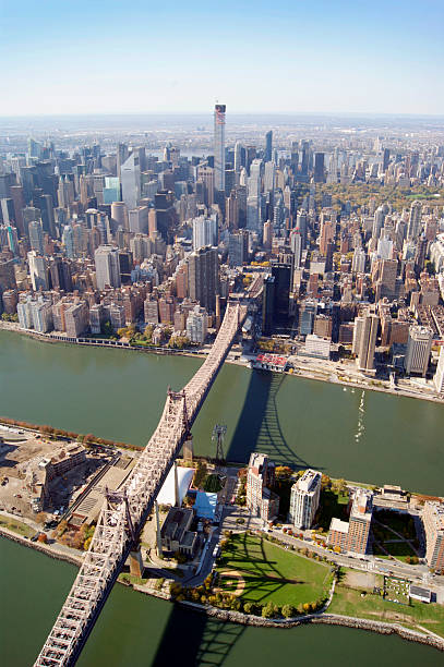 New York Queensboro Bridge New York's Queensboro Bridge Aerial Photo, also known as the 59th Street Bridge – because its Manhattan end is located between 59th and 60th Streets – and officially titled the Ed Koch Queensboro Bridge, is a cantilever bridge over the East River in New York City that was completed in 1909. It connects the neighborhood of Long Island City in the borough of Queens with Manhattan, passing over Roosevelt Island. It carries New York State Route 25 and is the westernmost of the four East River spans that carry a route number: NY 25 terminates at the west (Manhattan) side of the bridge, which once carried NY 24 and NY 25A as well. The bridge is flanked on its northern side by the freestanding Roosevelt Island Tramway. The bridge was, for a long time, simply called the Queensboro Bridge, but in March 2011, the bridge was officially renamed in honor of former New York City mayor Ed Koch. new york marathon photos stock pictures, royalty-free photos & images