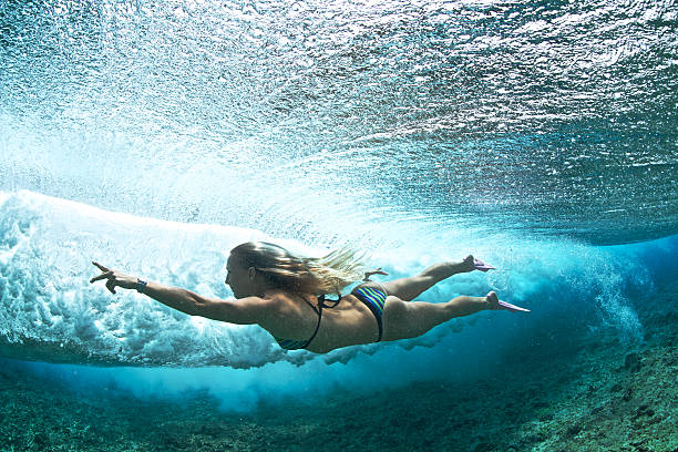garota atrás de uma onda quebrando bodysurfs - bodysurfing - fotografias e filmes do acervo