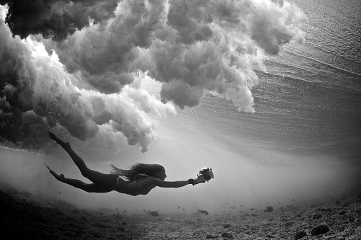 Black and white of girl swimng with a camera