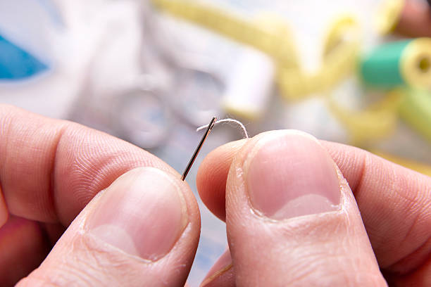 istock fingers of a tailor threading a needle 509550402