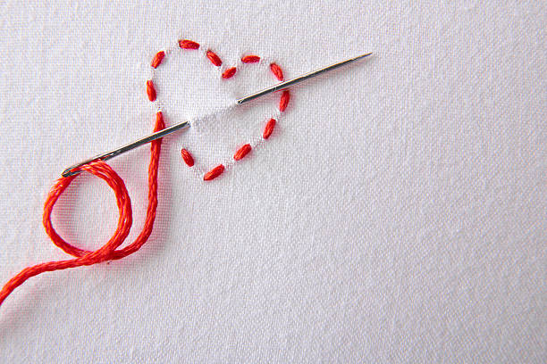 ricamo con cuore rosso in panno bianco primo piano - working tailor stitch sewing foto e immagini stock