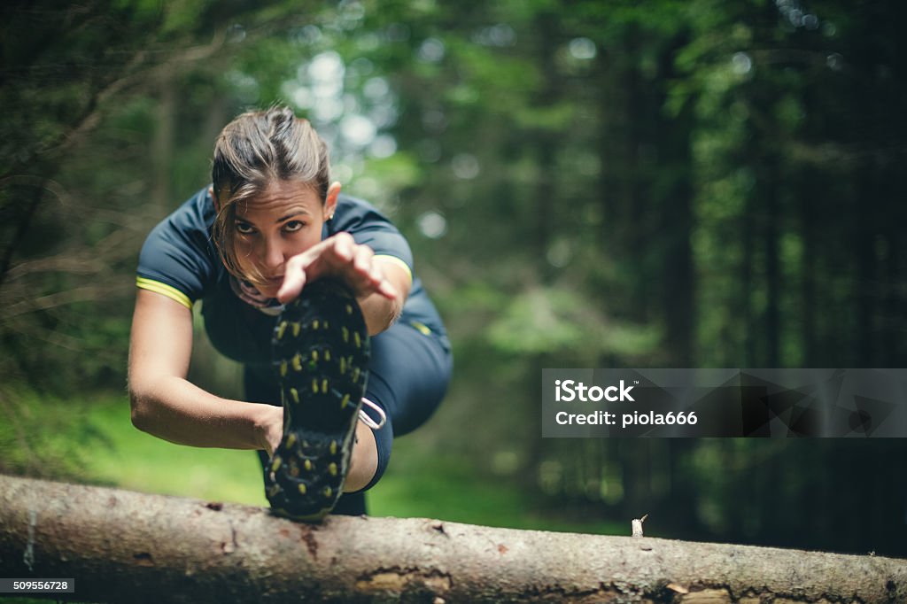Woman athlete stretching in the forest after running A woman exercise trail running in a green and wet forest, and stretch her muscle after the activity Running Stock Photo