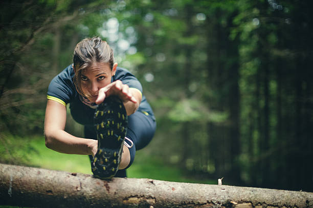 mulher de atleta de alongamento após uma corrida na floresta - running jogging footpath cross country running - fotografias e filmes do acervo