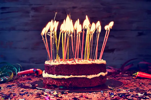 Photo of birthday cake with some lit candles, filtered