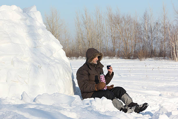 The man sitting near an igloo and drinking tea