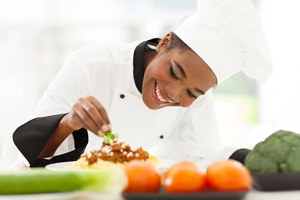 african female chef garnishing spaghetti dish