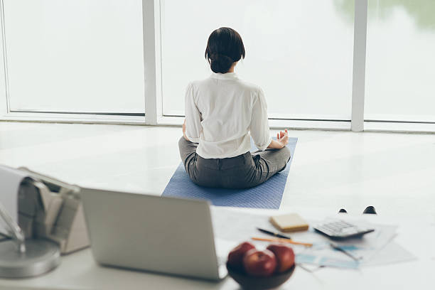 méditer dans la matinée - yoga business women indoors photos et images de collection