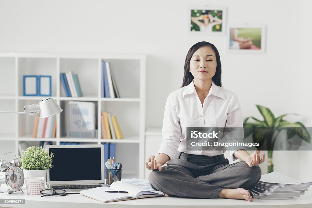 Meditation Female office worker meditating on her work place Zen-like Stock Photo