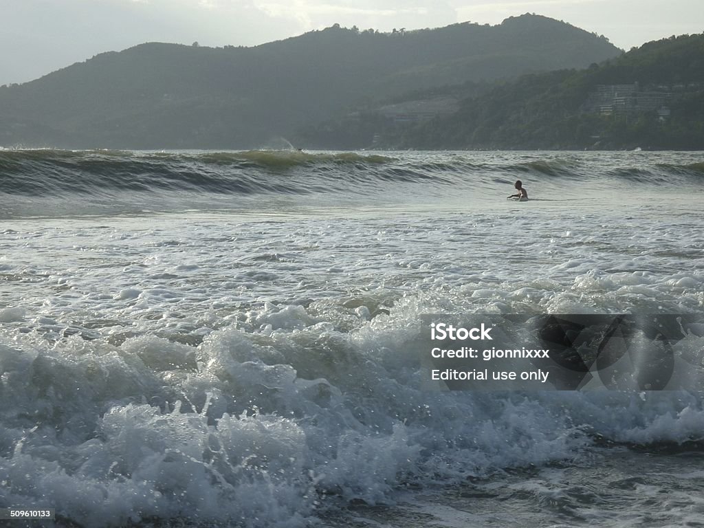 Waves crashing on Patong beach, Phuket Thailand Patong, Thailand - June 15, 2014: guy getting some big waves in Patong beach. Patong is Phuket island's busiest tourist destination. Adult Stock Photo