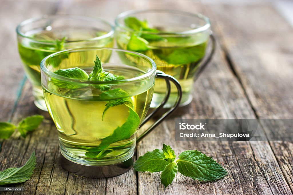 Hot mint tea in glass cup Hot mint tea in glass cup on wooden background, selective focus Alternative Therapy Stock Photo